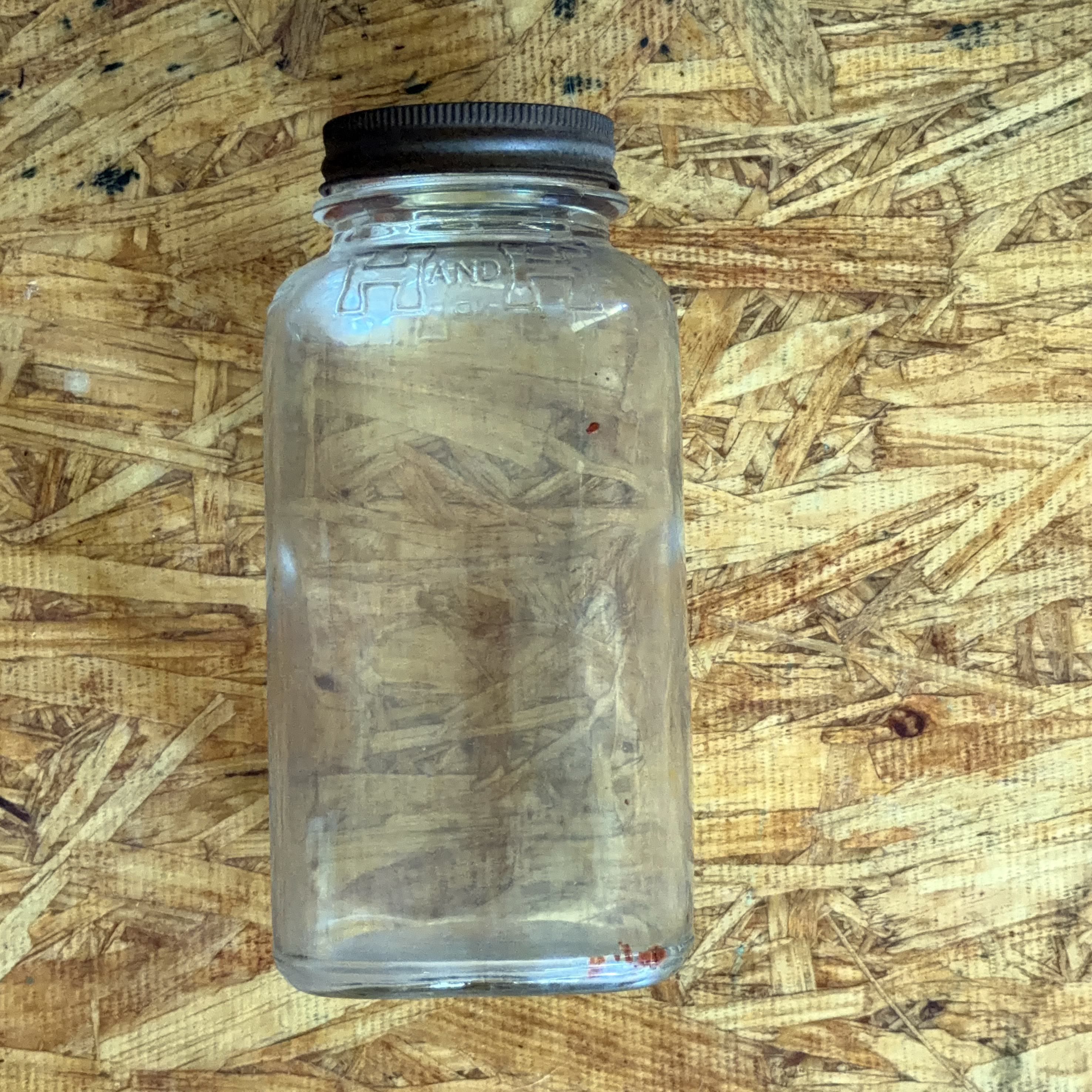 H and H one-pound smooth-body Crystalvac jar with no paper label, brown oxidized screw lid, H AND H embossed in blocks around the shoulder, photographed 2026-07-21
