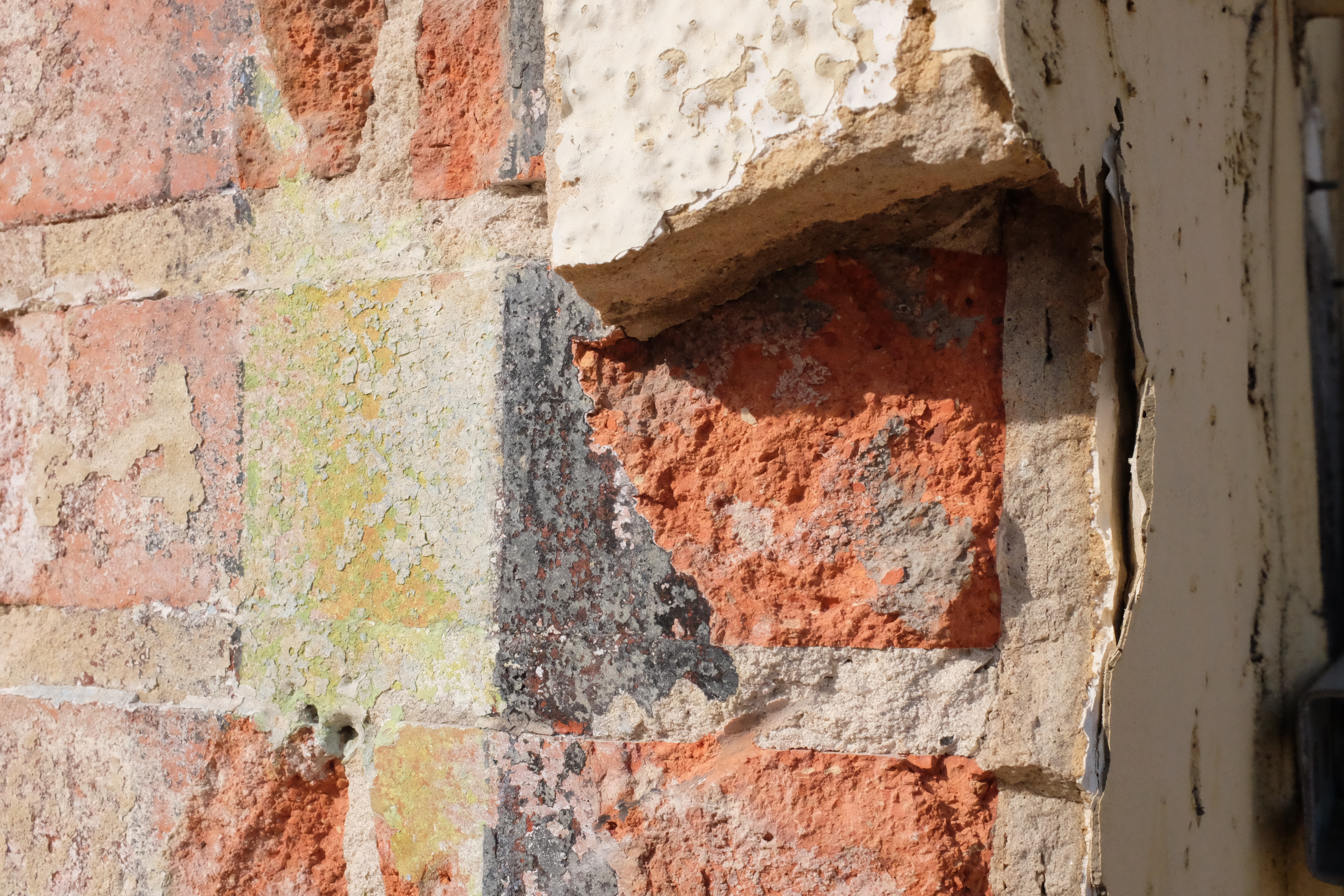 Stucco edge meeting scored brick; yellow and black paint bands