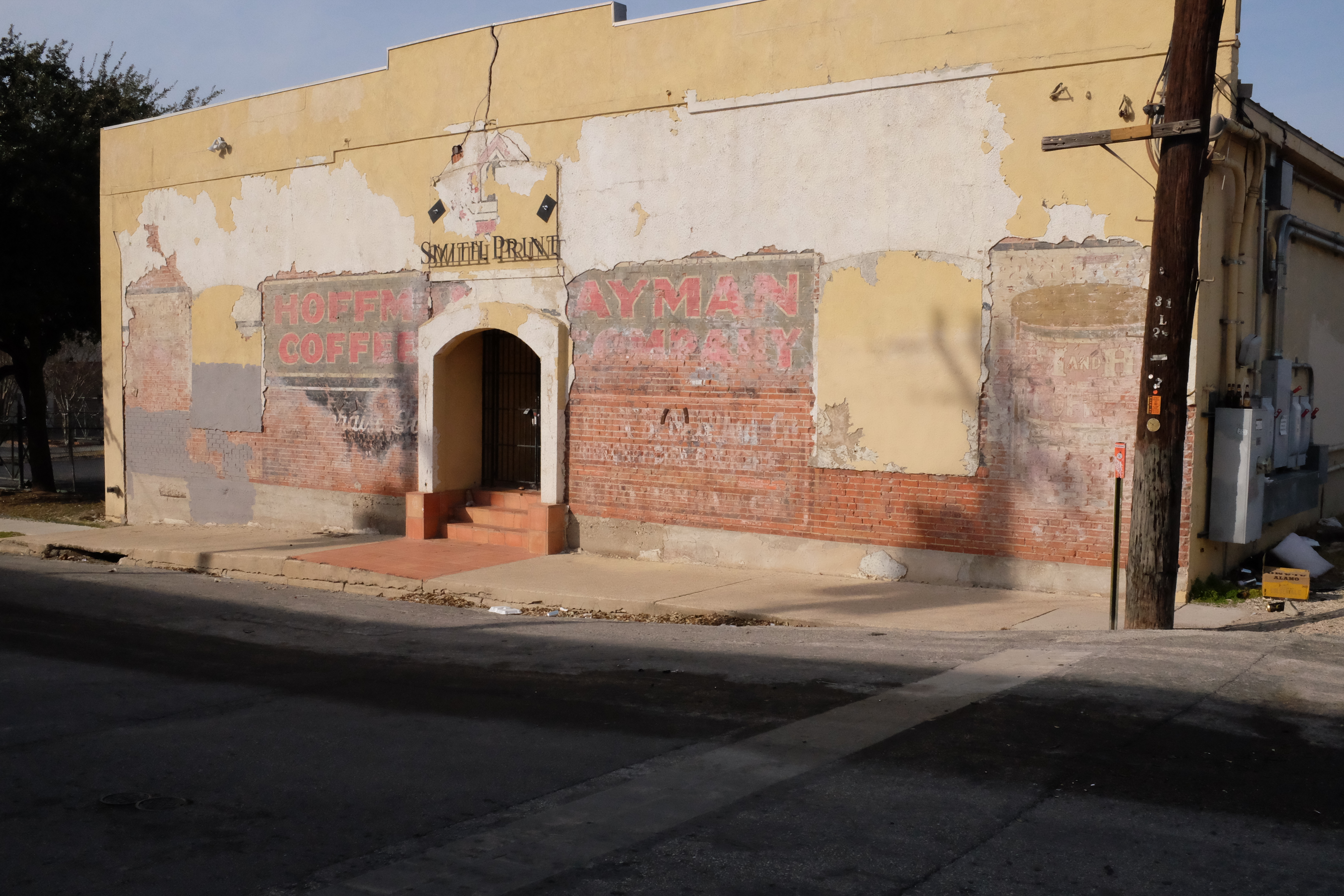 Structural clay tile wall — stucco loss; chain-link and barbed wire in foreground