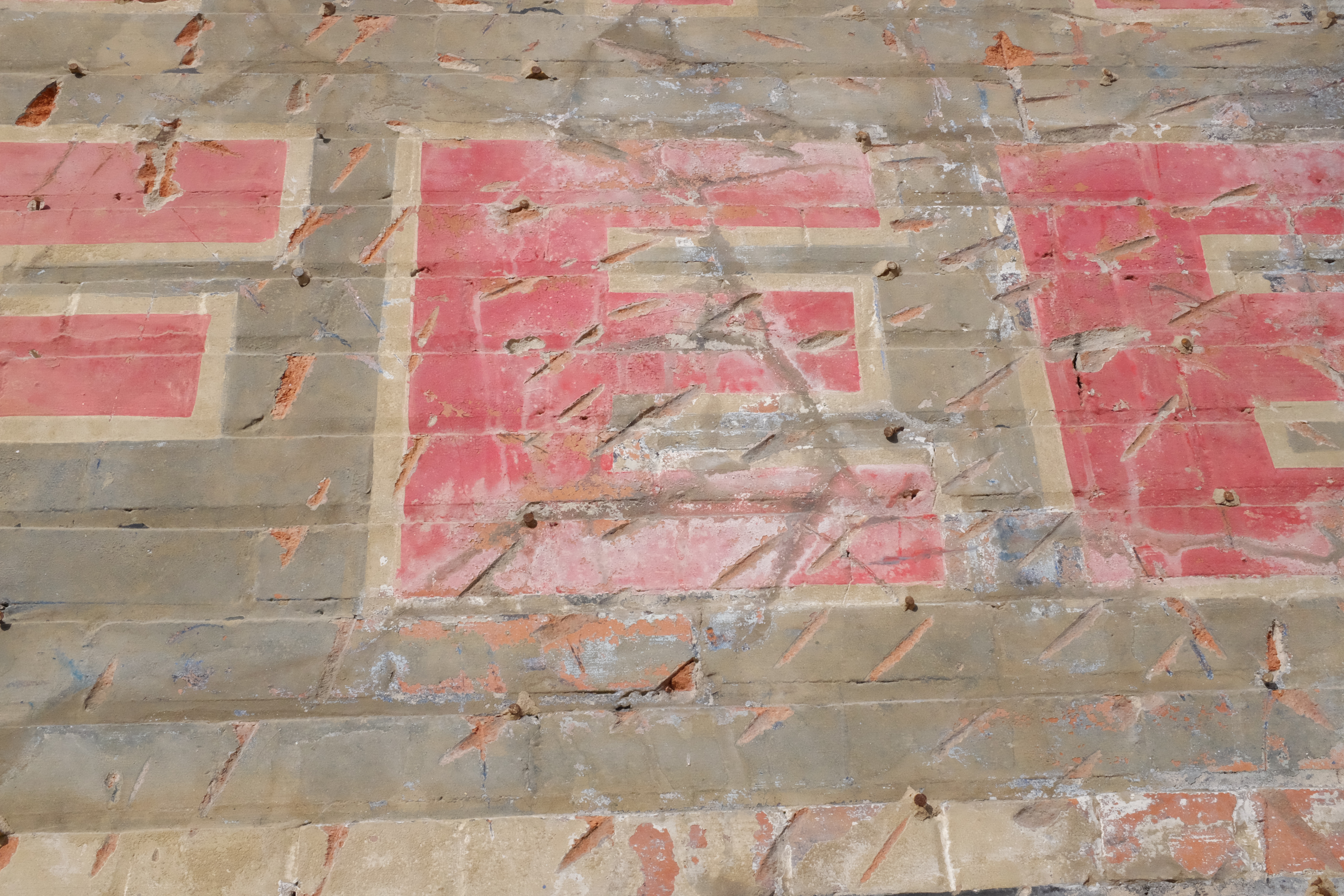 Red block letter with cream outline — scored masonry and nail studs