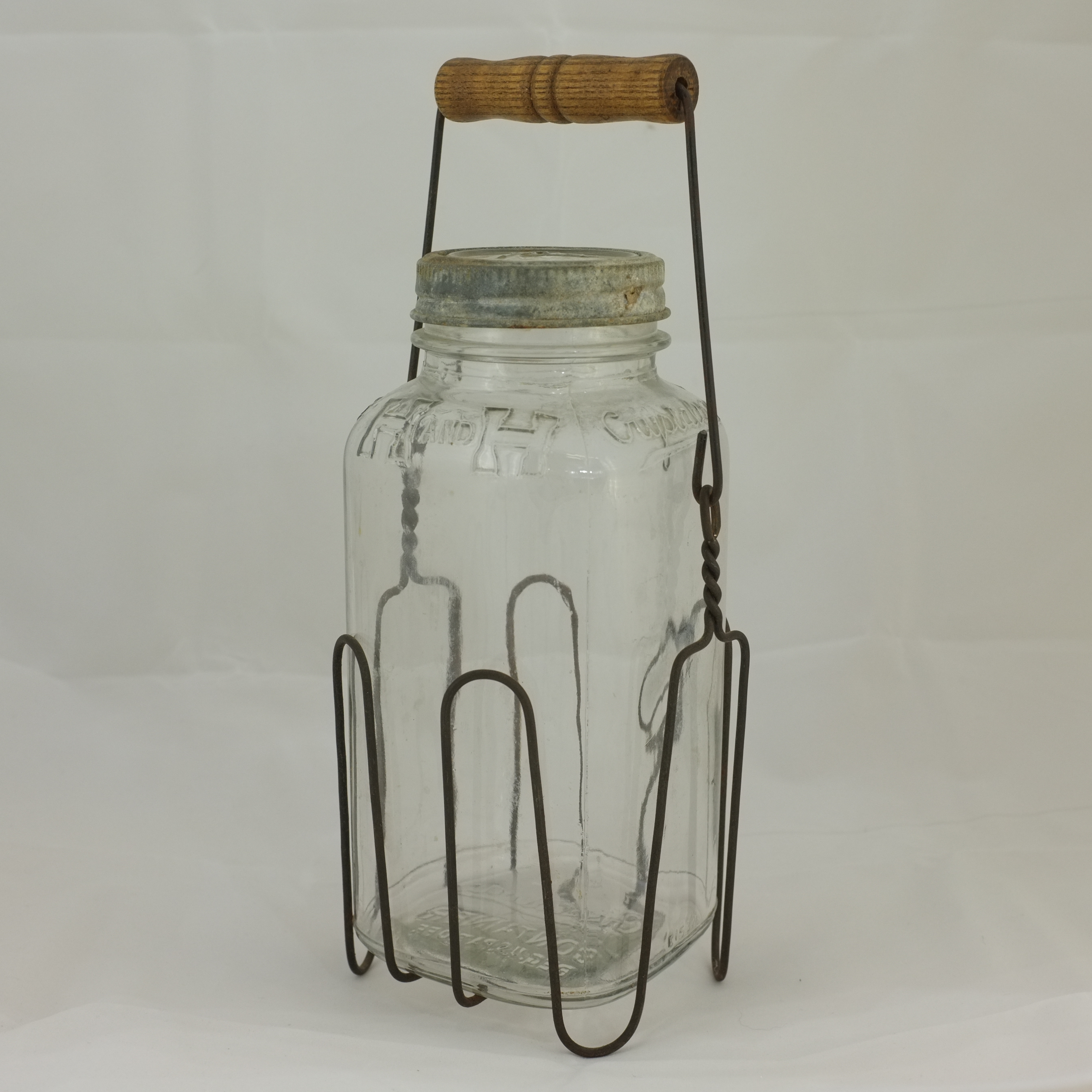 Small H and H Crystalvac-type jar in wire basket with wood handle, Ball glass and zinc top