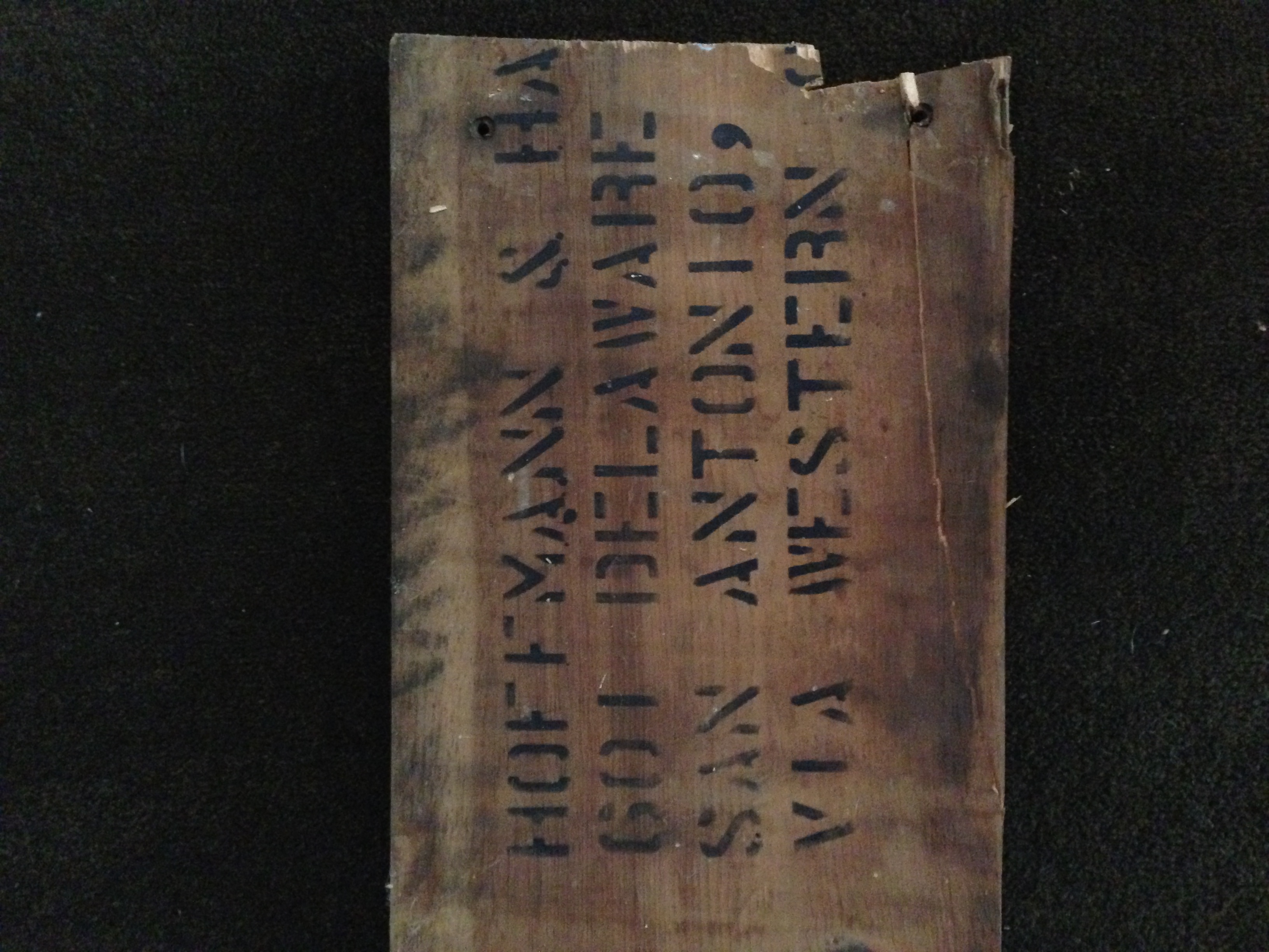 Weathered crate board with broken right edge — same Hoffmann & Hayman address stencil, nail holes along the split