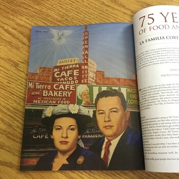 Edible San Antonio Aug/Sep 2016, Issue No. 18, open on a wooden desk to the La Familia Cortez 75 Years feature — painted portrait of Pedro and Cruz Cortez in front of the Mi Tierra Cafe and Bakery storefront with the Master Chef Coffee chef mascot visible on the adjacent building wall