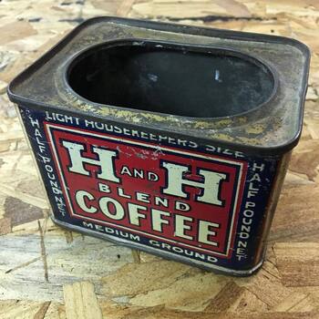 **Instagram** media export **17874198988014847** — **high-angle three-quarter** photograph on a **tan OSB** work surface — **small rectangular H and H Blend Coffee tin** (**press-in oval lid missing**, **raw rolled rim** showing **rust bloom**), lithographed in **navy, lipstick red, and white**: **upper blue rail** reading **LIGHT HOUSEKEEPERS SIZE**, **lower blue rail** **MEDIUM GROUND**, **vertical side margins** **HALF POUND NET**, central **red panel** carrying outsized **white serif H** characters with **black keylines**, small white **AND** between the **H crossbars**, **BLEND** tucked under the right stem, and **COFFEE** in **heavy white block caps** across the footer band; **scuffs, scratches, and enamel loss** through the red field — **second half-pound Blend retail format** in the collection (**painted tin** decoration) beside the **April 2019 paper-label half-pound** study **sequenced above** in **this gallery**, and in the same **Blend / Medium Ground** graphic family as the **one-pound rectangular tin** in **[the Mac Johanson medium-ground frame](/assets/images/gallery/h-and-h-blend-coffee-1lb-tin-medium-ground.jpg)**