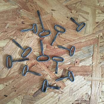 **Instagram** media export **17891393647003169** — **plan-view** photograph on **tan OSB** chipboard — loose **lot of roughly a dozen** vintage **rolled-tin strip keys** (**T-loop handles**, **flat shanks**, **narrow slotted tips**) of the sort used to **peel the scored lid strip** on **keywind vacuum-packed coffee tins** (the same mechanical family as **sardine-can** and **sanitary** tin keys) — **dull steel patina**, mixed azimuth scatter across the bench — **collection tooling stock** for servicing **H and H** and other **early-20th-century** keywind cans already in **this gallery**, including **[the 2026 one-pound keywind second example](/assets/images/gallery/2026-04-23-h-and-h-coffee-keywind-tin-second-example.jpg)** (photographed **without** a key mounted) and **[Family Size keywind tin](/assets/images/gallery/handh-family-size-keywind-ig.jpg)**