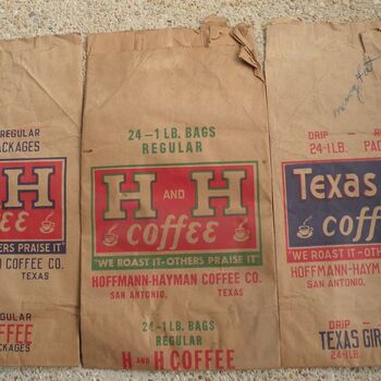 Three large paper sacks laid flat side by side — an H and H Coffee '24 — 1 LB. BAGS REGULAR' sack with the red-and-cream Hoffmann-Hayman label, a second H and H sack behind it, and a Texas Girl Coffee '24 — 1 LB. BAGS DRIP' sack with the blue-and-red label