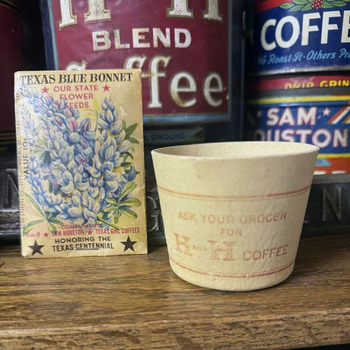 A 1936 Texas Blue Bonnet Centennial seed packet ('Compliments Sam Houston · Texas Girl Coffees · Honoring the Texas Centennial') beside a small cream-and-red H and H Coffee paper sampler cup printed 'Ask Your Grocer for H and H Coffee', staged in front of H and H Blend and Sam Houston coffee tins